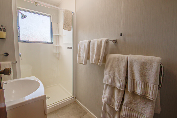 Bathroom with enclosed shower unit,  sink and towel rails holding several towels.